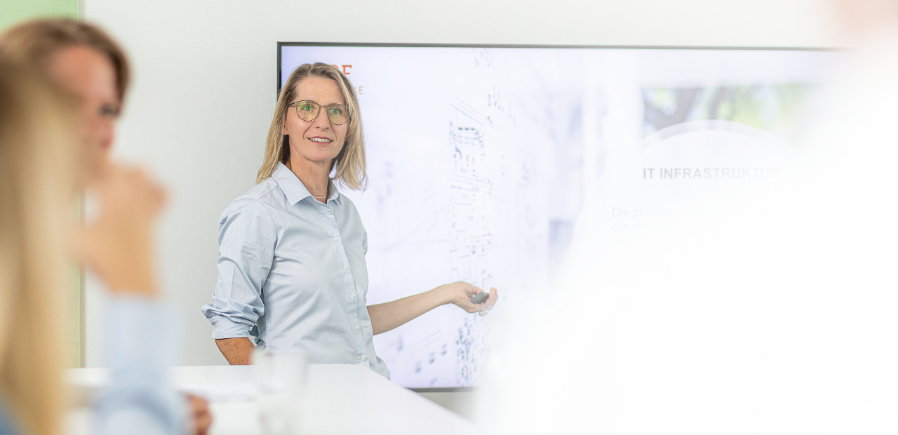 Seminartrainerin präsentiert vor einem großen Monitor